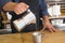 Male Barista preparing fresh espresso in coffee maker for customer in a fancy coffee shop. Cafe owner serving a client at the