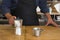 Male Barista preparing fresh espresso in coffee maker for customer in a fancy coffee shop. Cafe owner serving a client at the
