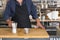 Male Barista preparing fresh espresso in coffee maker for customer in a fancy coffee shop. Cafe owner serving a client at the