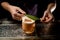 Male bartender decorated a glass with creamy color cocktail drink with a green tropical leaf