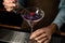 Male bartender decorated purple alcoholic cocktail with a red flower by tweezers