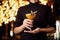 Male bartender in the purple shirt serving yellow alcoholic cocktail in the glass with a dried lemon and leaf