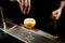 Male bartender sprinkles alcohol drink on a bar counter