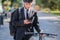 Male bicycle commuter in a suit and helmet with a phone.