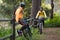 Male biker cycling while female biker sitting on a fence