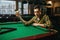 Male billiard player holds white ball at the table