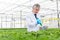 Male biochemist using pipette on herbs in plant nursery