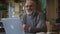 Male biologist professor is posing sitting at table with laptop in college library.