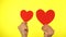 Male blogger hold in hands two little red hearts on a yellow background.