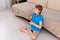 Male blonde child playing on video game console home, sitting on the sofa, gadget addiction