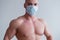 Male bodybuilder in a medical mask with muscular bare chest. The guy goes in for sports in quarantine. Respiratory