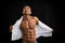Male bodybuilder taking off his shirt revealing muscular torso