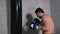 Male boxer training thai box exercise with combat bag in fight club Boxer in gloves kicking boxing bag while fight