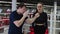 Male boxing coach shows the punch technic to his woman trainee