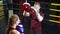 Male boxing instructor using boxing kick pads when training young woman in the ring.