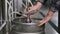 A male brewer connects a keg to a beer tank and fills it with beer. Close-up.