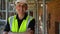 Male builder on construction building site standing on scaffolding with a arms folded laughing and smiling to camera