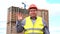 Male builder foreman, worker or architect on construction building site greeting by waving his hand