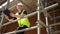 Male builder foreman, worker or architect working on construction building site standing on scaffolding wearing a hardhat