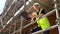 Male builder foreman worker on construction building site standing on scaffolding writing on clipboard