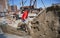 Male builder shoveling sand-cement mix at construction site.