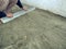 Male builder smooths the surface of a dry sand-cement mixture with aluminum plaster rule tool. Concept flooring or landscaping,