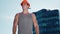 Male builder stands against background of a high-rise building. Handsome guy is hard worker in good shape with helmet on his head