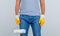 Male builder in t-shirt, jeans, gloves holding paint roller , front view