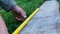 Male builder taking measurements of wooden board with a measuring tape or yardstick