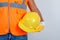 Male builder in uniform, jeans, gloves holding helmet in his hand , front view