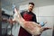 Male butcher standing by meat hanging on hook in meat shop