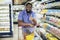 Male Buyer Shopping Groceries In Supermarket Standing With Shop Cart Indoors Showing Thumb Up