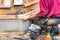 A male carpenter crouched down assembling a piece of wood on a house, outdoors