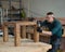 Male carpenter finishing work on wooden table in workshop.