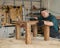 Male carpenter finishing work on wooden table in workshop.