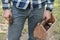 Male carpenter holds a hammer in one hand and a homemade wooden box with nails in the other, against a blurred