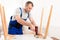 Male Carpenter Using Electric Drill Assembling Wooden Table In Studio