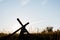 Male carrying a hand made wooden cross in a grassy field with a blue sky in the background