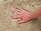 Male Caucasian hand in the salt sand on the beach.