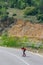 Male caucasian longboarder riding downhill on an empty road doing a speed tuck and grabbing the board while driving the longboard