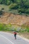 Male caucasian longboarder riding downhill on an empty road doing a speed tuck and grabbing the board while driving the longboard