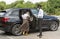 Male chauffeur opens the car door for his female client.