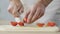 Male chef accurately cutting tomatoes in kitchen and adding it to dish, cooking