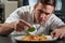 Male Chef Garnishing Plate Of Food In Professional Kitchen