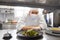 Male chef in mask with food at restaurant kitchen