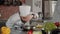 Male chef pouring shredded cheese on cooked food in frying pan