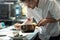 Male chef putting boiled mussels on plate while taking them out of metallic pan