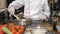 Male chef in restaurant s open kitchen is preparing pasta dish
