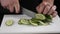 Male chief cook chopping vegetables, slicing cucumber on white board. Close up. Man on kitchen cooking natural and