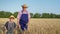 Male child holds hand of an elderly farmer holding ears of wheat and walks through a wheat field